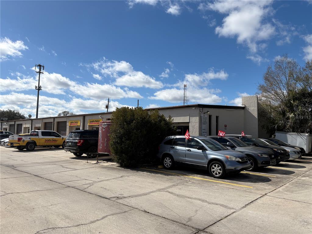 A commercial building exterior with a parking lot containing several cars and a truck — 9212 LAZY LANE, TAMPA, FL