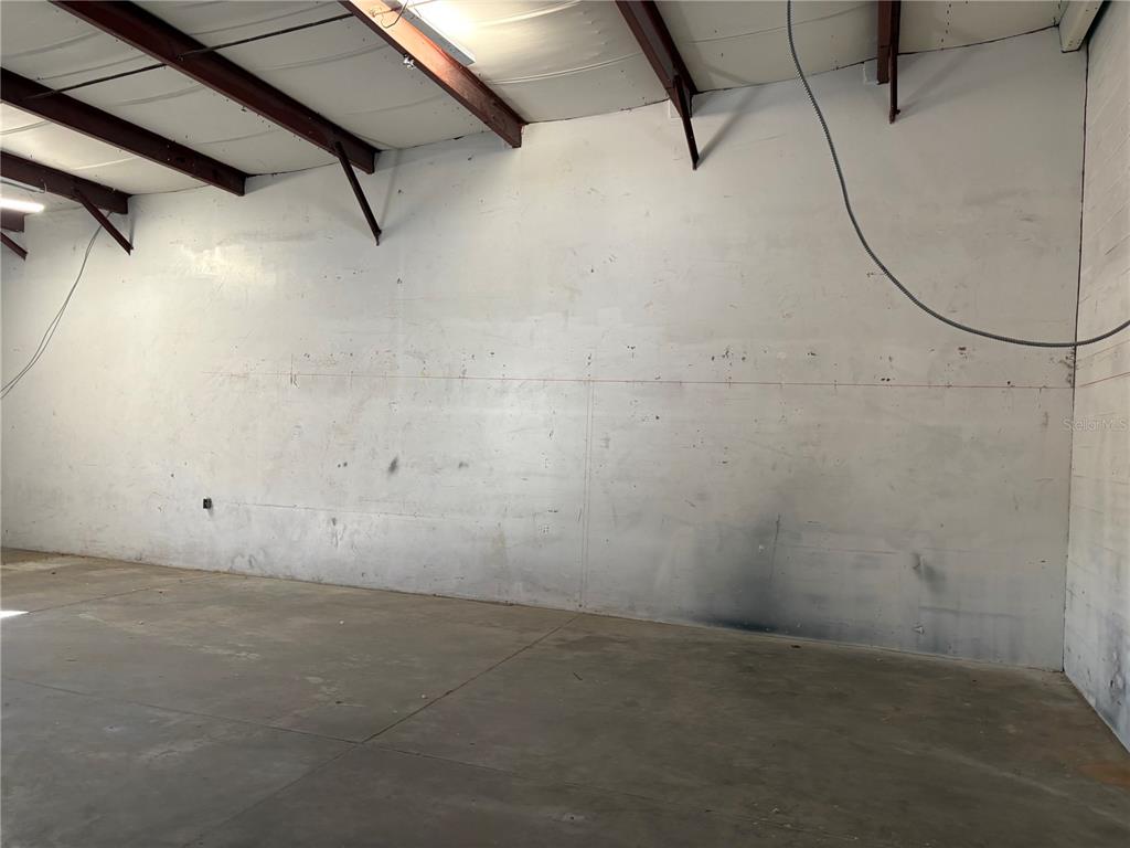 An empty industrial warehouse space features concrete floors, white walls, and exposed ceiling beams — 9212 LAZY LANE, TAMPA, FL