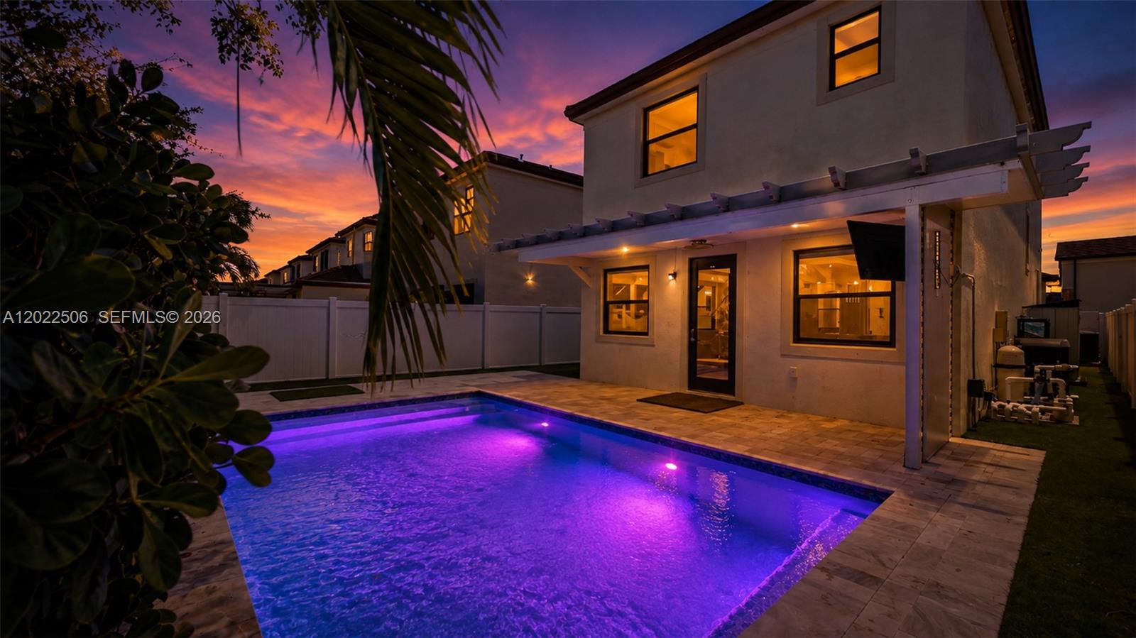 A two-story house with a backyard swimming pool illuminated by purple lights at sunset — 3567 W 110th Ter, Hialeah FL 33018, HIALEAH, FL