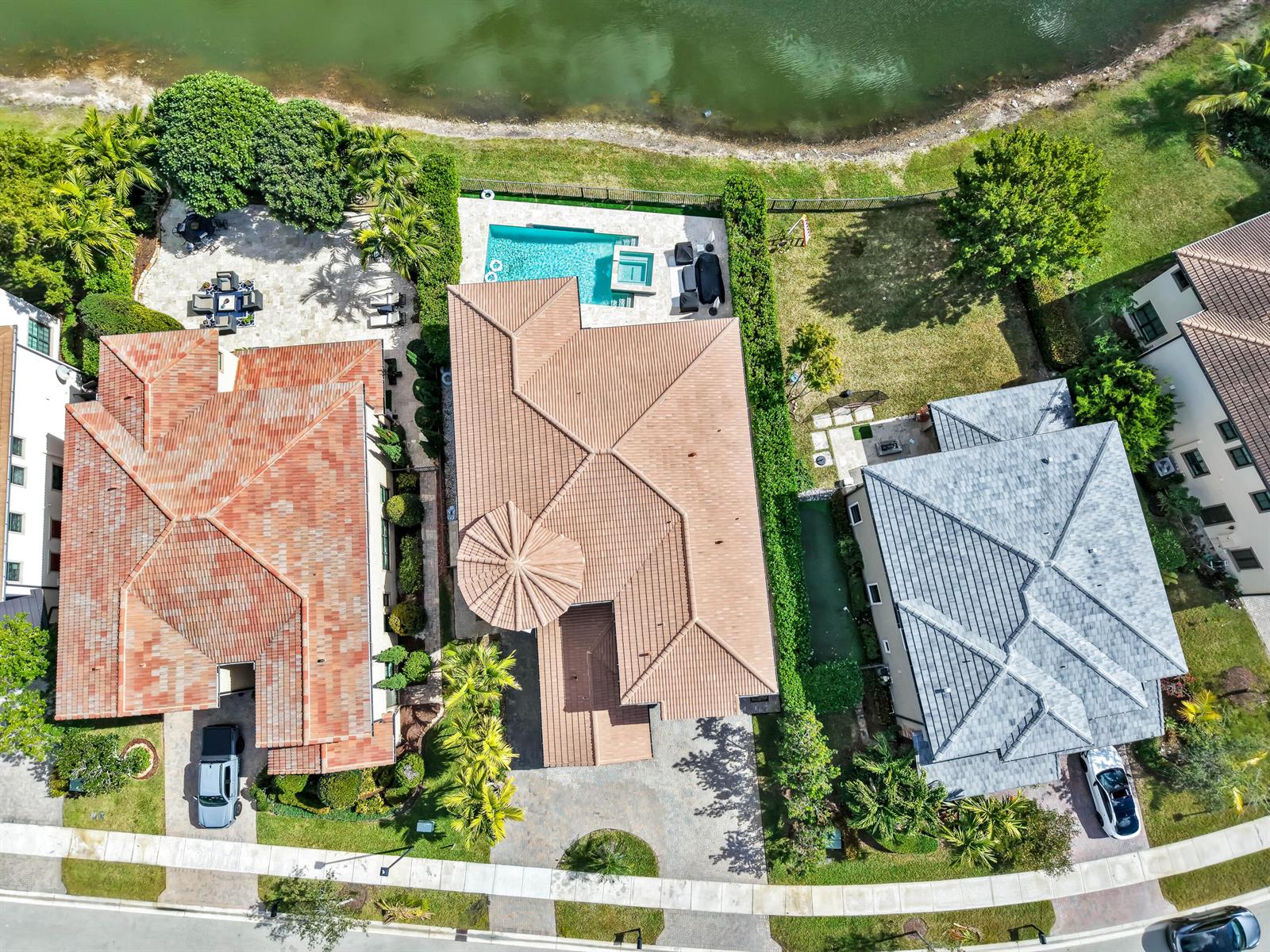 An aerial view shows three suburban houses with pools and driveways along a waterfront — 9040 W Watercrest Cir Circle W, Parkland FL 33076, PARKLAND, FL