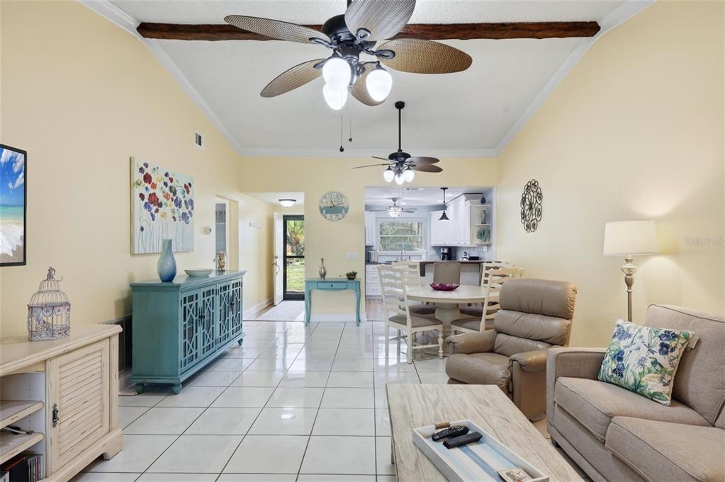 An open-concept living and dining area features white tile floors, ceiling fans, and yellow walls — 3663 LONGMEADOW UNIT 23, SARASOTA, FL