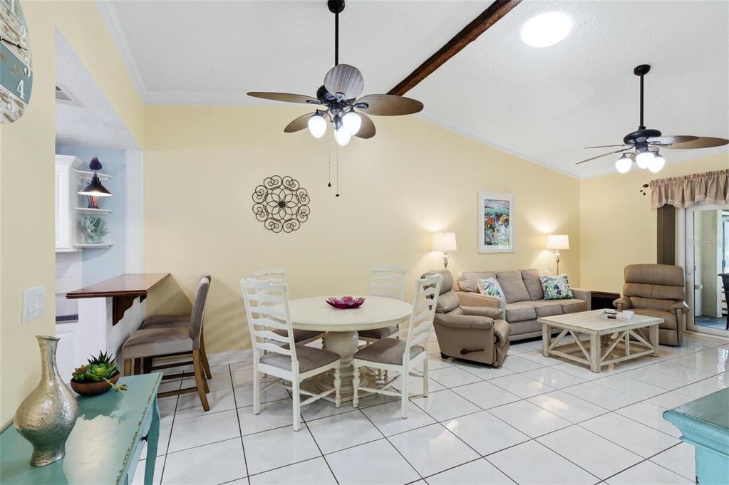 A bright open-concept living and dining area features white tile floors and vaulted ceilings — 3663 LONGMEADOW UNIT 23, SARASOTA, FL