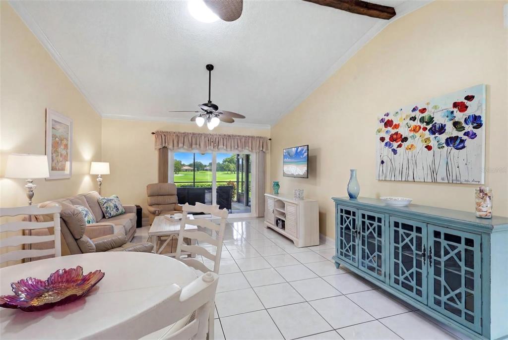 A living and dining area features white tile floors, a blue cabinet, and a golf course view — 3663 LONGMEADOW UNIT 23, SARASOTA, FL