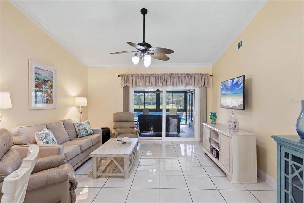 A living room features light-colored tile floors, a ceiling fan, and sliding doors to a patio — 3663 LONGMEADOW UNIT 23, SARASOTA, FL
