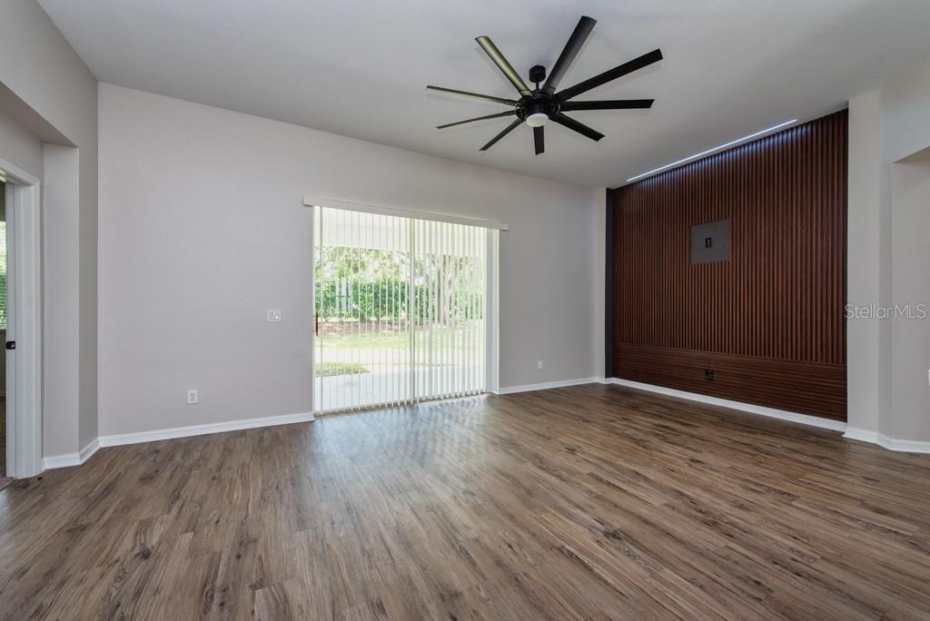 A living room features wood-look flooring, a ceiling fan, and a wood-slat accent wall — 11104 HOLLY CONE DRIVE, RIVERVIEW, FL