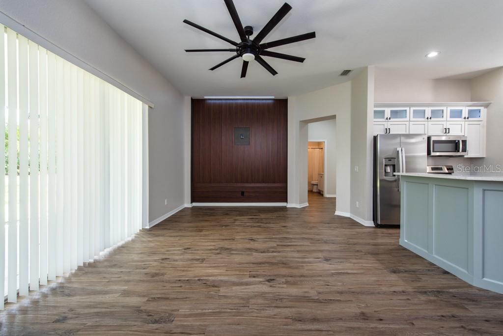 A living area features wood-look flooring, a dark wood accent wall, and a ceiling fan — 11104 HOLLY CONE DRIVE, RIVERVIEW, FL