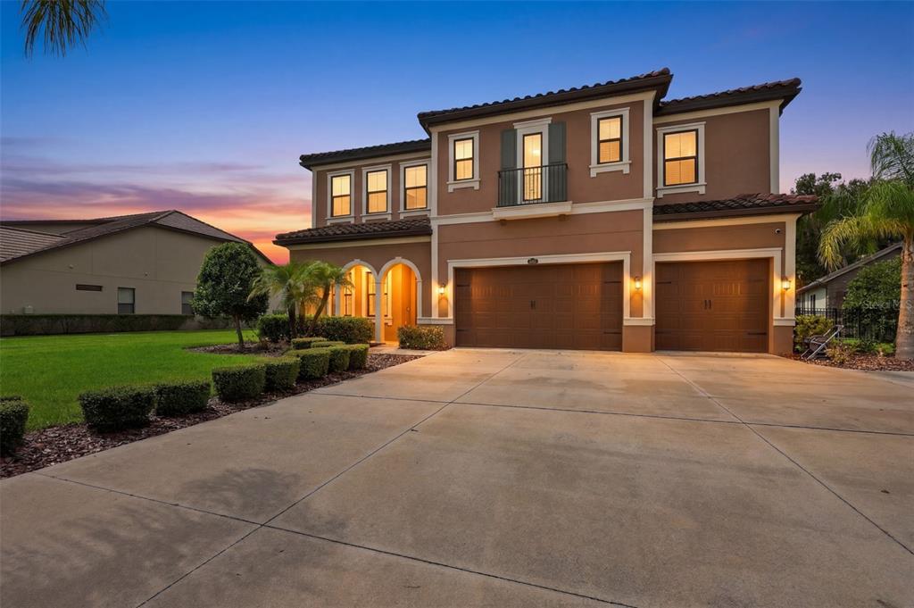 A two-story house with a three-car garage and a concrete driveway at sunset — 3225 CORDOBA RANCH BOULEVARD, LUTZ, FL