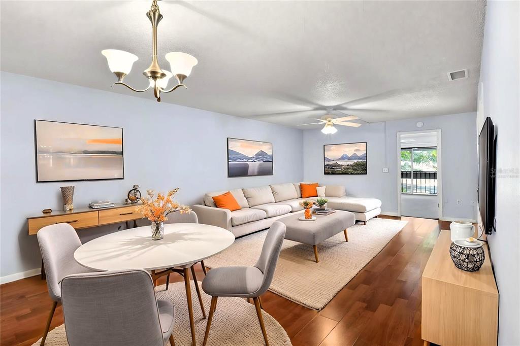 A living and dining area features light blue walls, hardwood floors, and a sectional sofa — 1810 VILLAGE CT, MULBERRY, FL