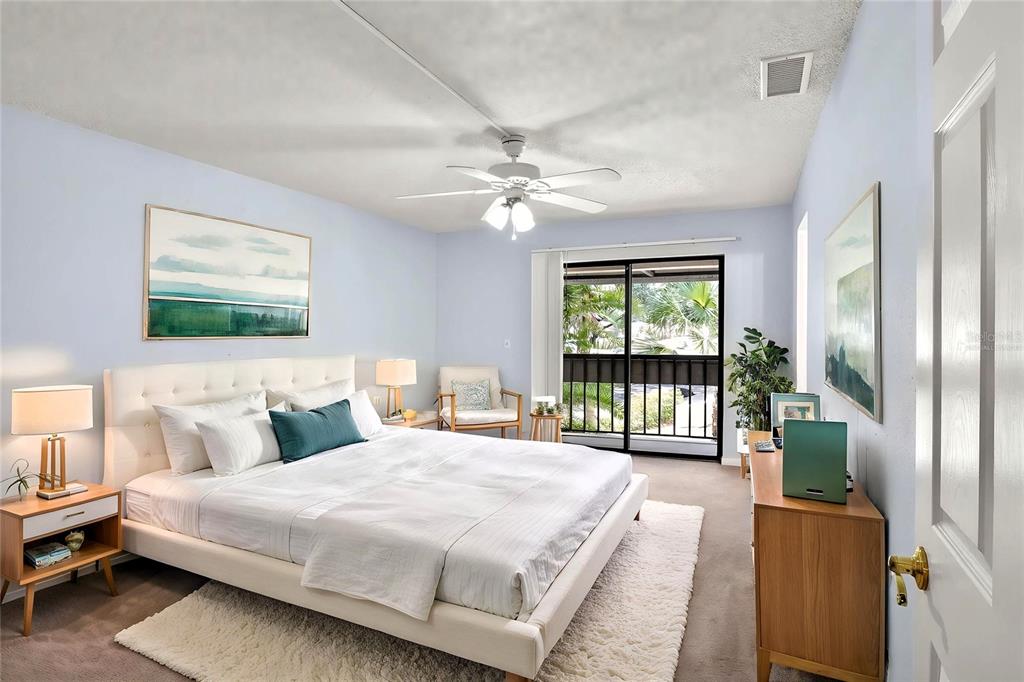 A bedroom features a white upholstered bed, a ceiling fan, and a sliding glass door — 1810 VILLAGE CT, MULBERRY, FL