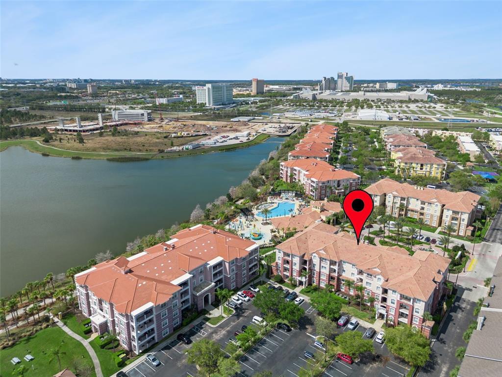 An aerial view shows a multi-story apartment complex with red tile roofs near a lake — 4862 CAYVIEW AVENUE UNIT 403, ORLANDO, FL