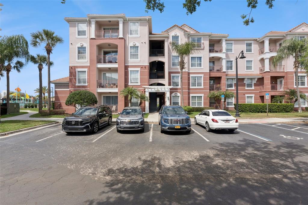 A multi-story apartment building with a parking lot in front containing four parked cars — 4862 CAYVIEW AVENUE UNIT 403, ORLANDO, FL