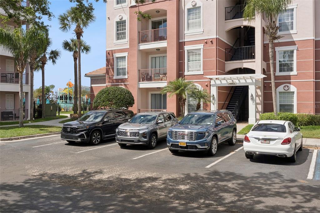 A multi-story apartment building exterior with four parked cars in the foreground — 4862 CAYVIEW AVENUE UNIT 403, ORLANDO, FL