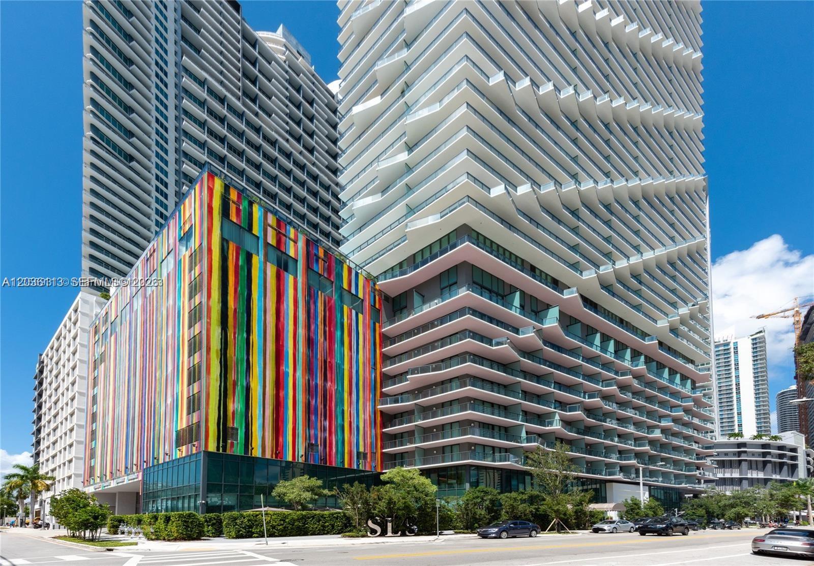 A colorful, vertically striped building stands next to a modern high-rise with tiered balconies — 1300 S Miami Ave # 1103, Miami FL 33130, MIAMI, FL