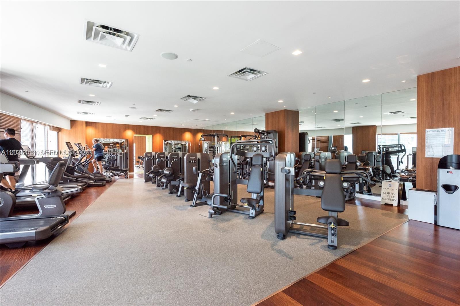 A modern fitness center features rows of weight machines, treadmills, and mirrored walls — 1300 S Miami Ave # 1103, Miami FL 33130, MIAMI, FL