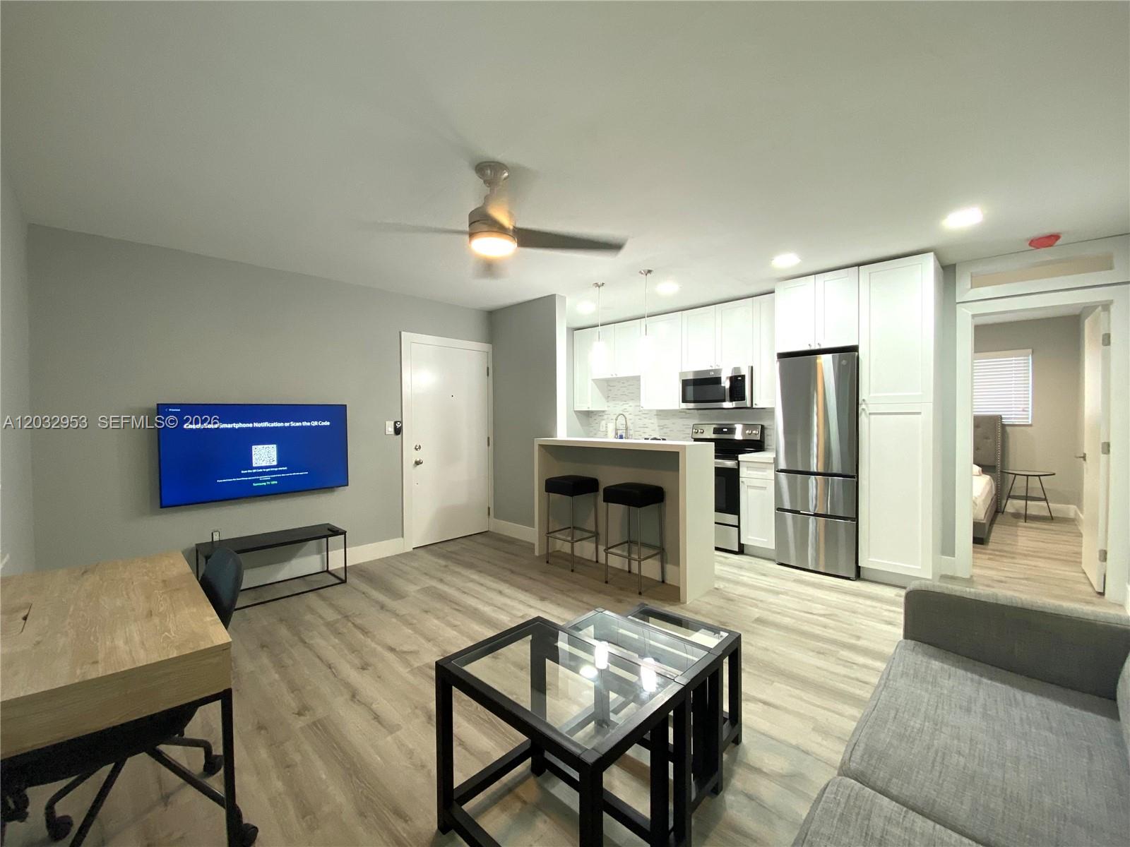 A modern living room and kitchen area with light wood floors and white cabinetry — 7901 SW 64 AVE # 18, South Miami FL 33143, SOUTH MIAMI, FL