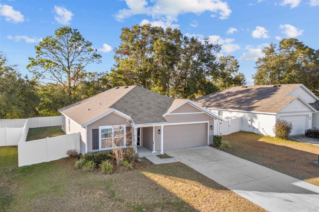 An elevated view of a single-story suburban house with a tan exterior and concrete driveway — 896 NW 253RD DRIVE, NEWBERRY, FL