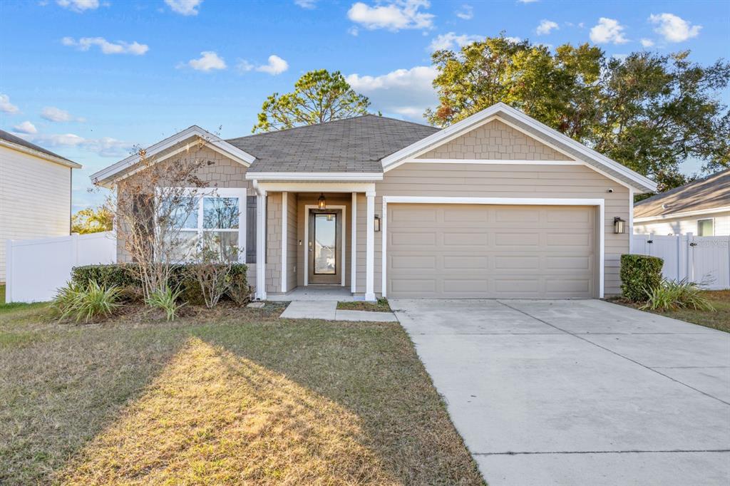 A single-story house with tan siding, a two-car garage, and a front porch — 896 NW 253RD DRIVE, NEWBERRY, FL
