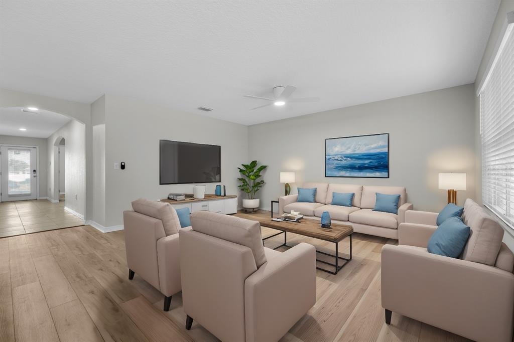 A living room features light wood floors, a beige sofa, two armchairs, and a television — 896 NW 253RD DRIVE, NEWBERRY, FL