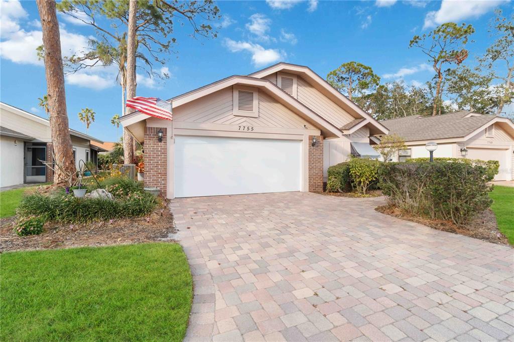A single-story house with a brick-accented garage and a paved driveway under a blue sky — 7755 PINE TRACE DRIVE UNIT 7755, SARASOTA, FL