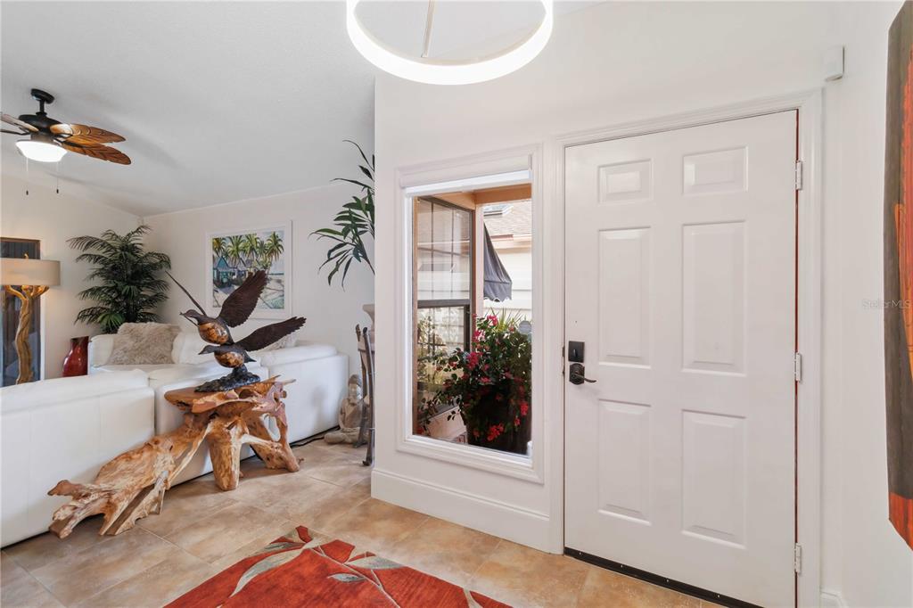 An entryway features a white door, a side window, tile flooring, and a living area — 7755 PINE TRACE DRIVE UNIT 7755, SARASOTA, FL