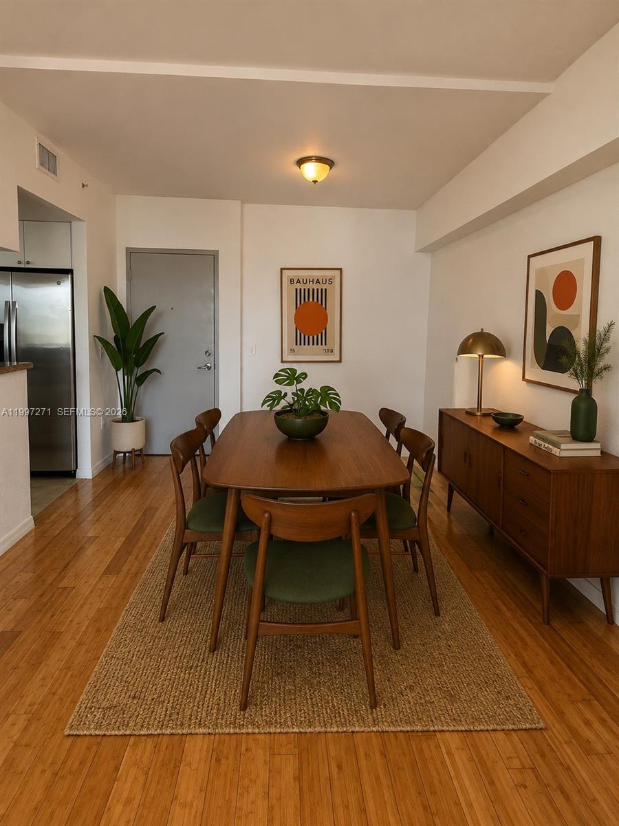 A dining room features a wooden table, six green chairs, a sideboard, and wall art — 36 NW 6th Ave # 504, Miami FL 33128, MIAMI, FL
