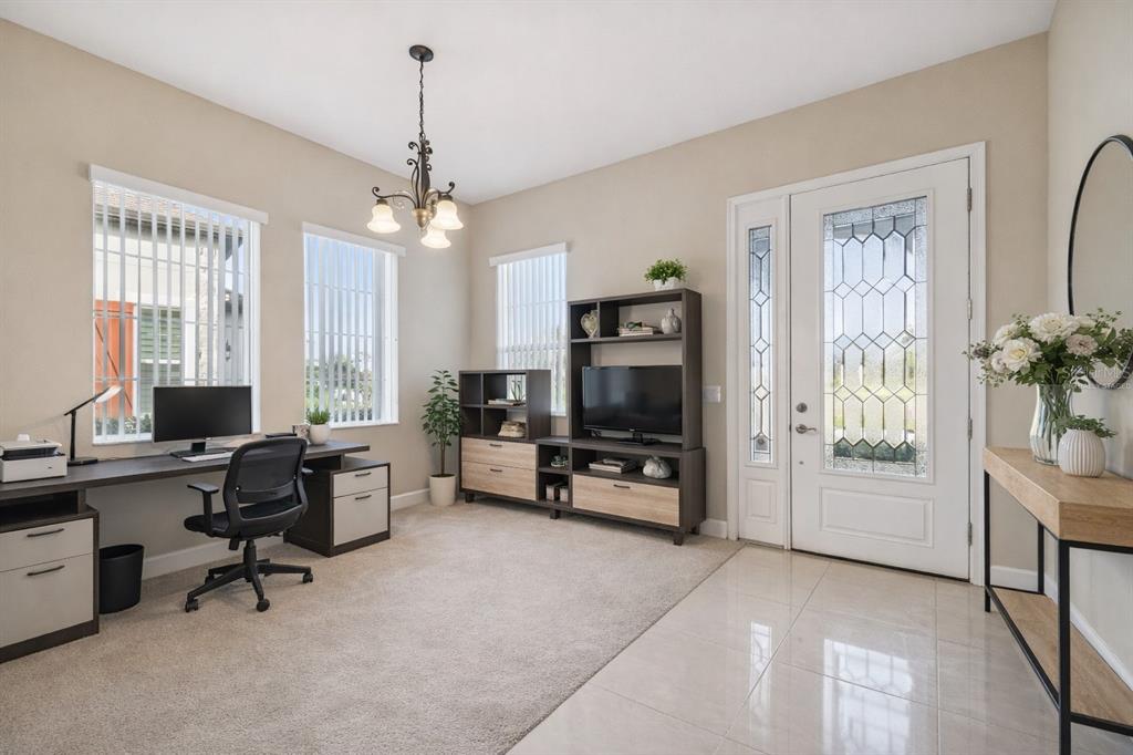 A home office with a desk, shelving unit, and front door with glass panels — 4155 BARLETTA COURT, WESLEY CHAPEL, FL