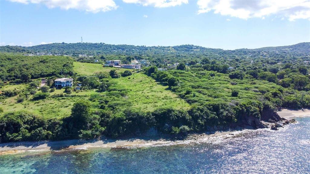 An aerial view shows a coastal hillside property with green vegetation and a rocky shoreline — 53 CALLE CANON, VIEQUES, PR