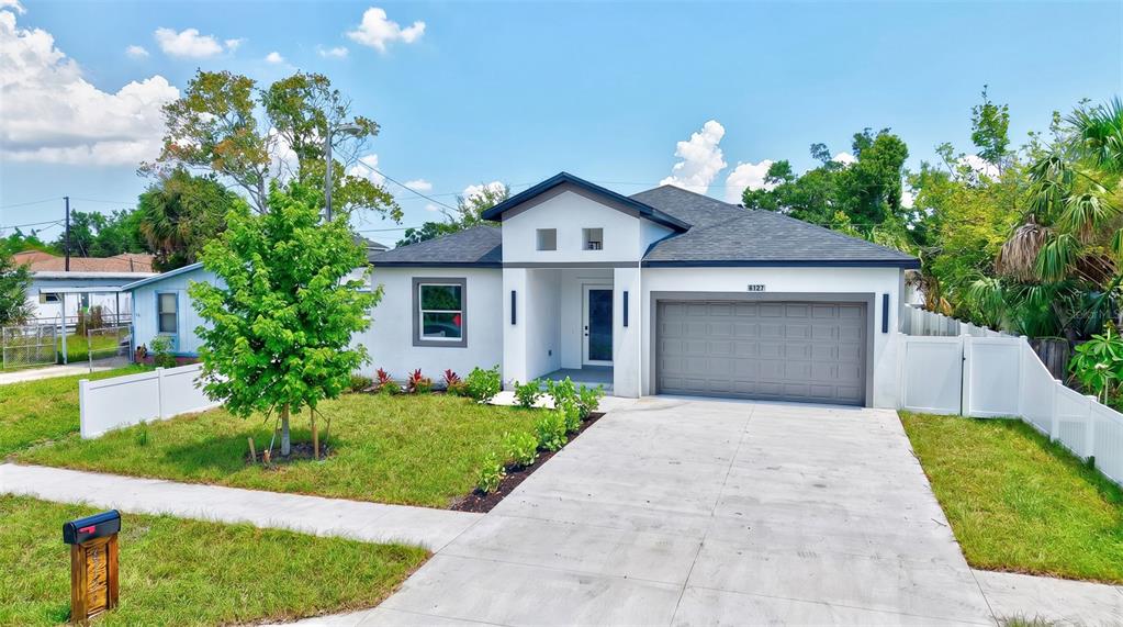 A modern, single-story house with a white exterior, gray garage door, and a concrete driveway — 6127 105TH TERRACE, PINELLAS PARK, FL