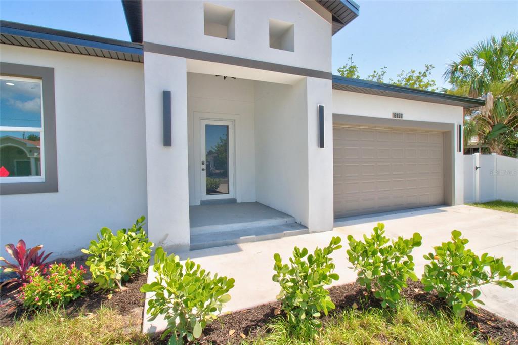 A modern single-story house exterior features a white stucco facade, a garage, and a front entrance — 6127 105TH TERRACE, PINELLAS PARK, FL