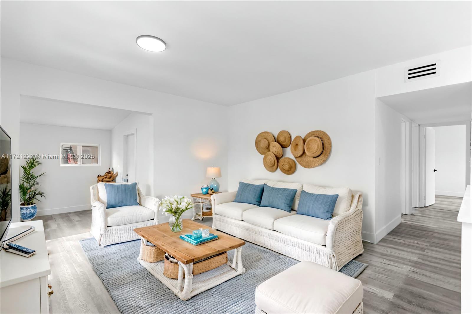 A bright living room features white wicker furniture, a wooden coffee table, and straw wall decor — 1560 NE 42nd Ct, Pompano Beach FL 33064, POMPANO BEACH, FL