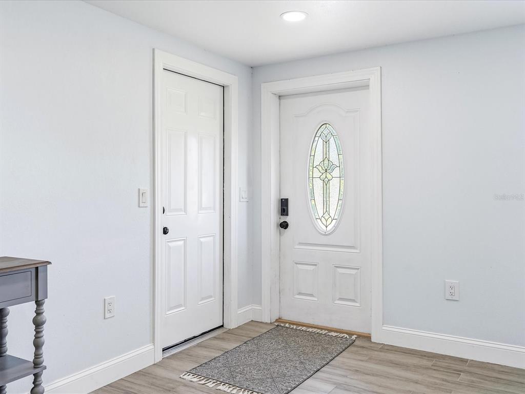 An entryway features light-colored walls, wood-look flooring, a front door with a glass insert, and a closet — 13641 DRYSDALE AVENUE, PORT CHARLOTTE, FL