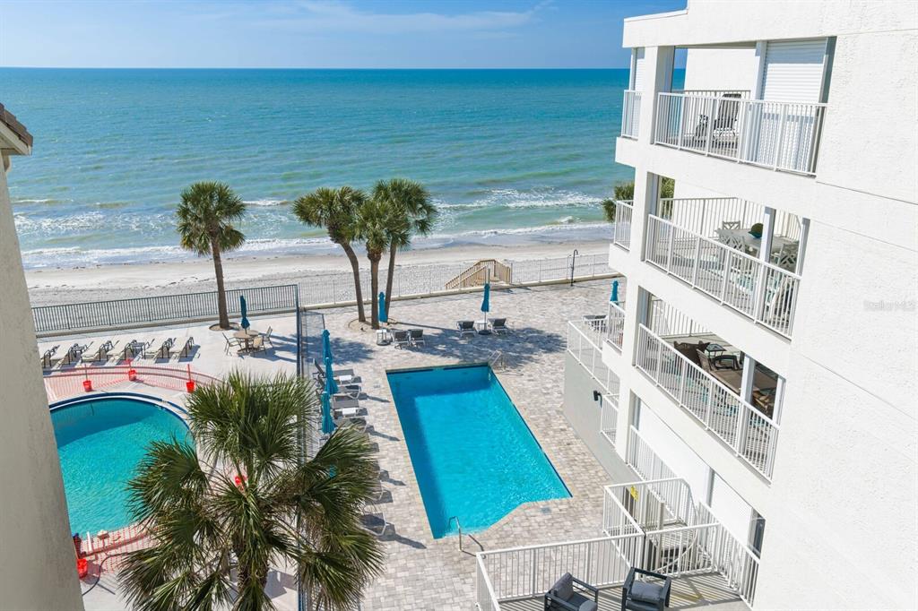 An elevated view of a beachside condominium complex featuring two swimming pools and ocean views — 16332 GULF BOULEVARD UNIT 3B, REDINGTON BEACH, FL