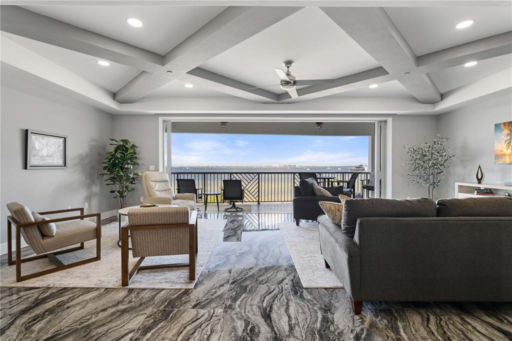 A living room with marble floors, a coffered ceiling, and large sliding doors opening to water — 1425 PARK BEACH CIRCLE UNIT 132, PUNTA GORDA, FL