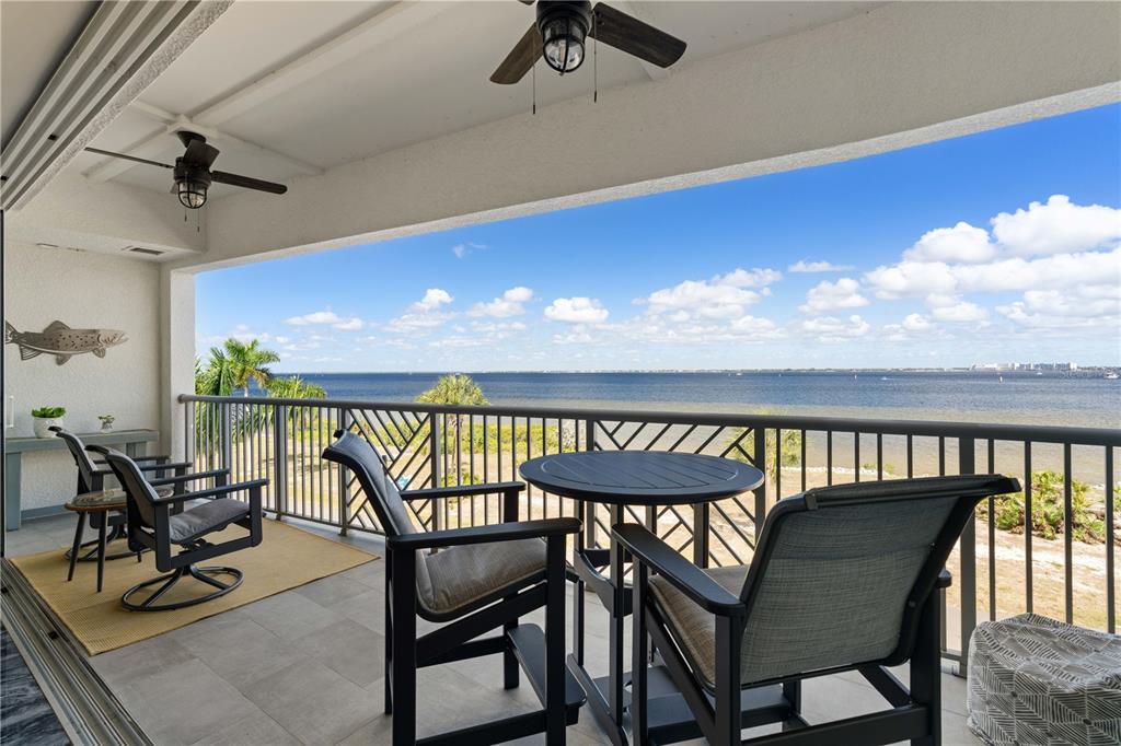A covered balcony features outdoor furniture, ceiling fans, and a view of the water — 1425 PARK BEACH CIRCLE UNIT 132, PUNTA GORDA, FL