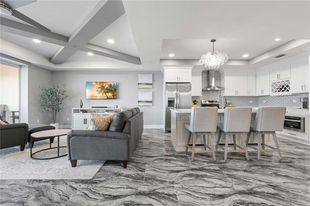 An open-concept living room and kitchen featuring gray marble tile flooring and white cabinetry — 1425 PARK BEACH CIRCLE UNIT 132, PUNTA GORDA, FL