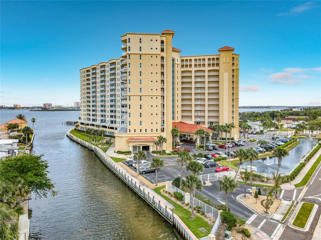 An aerial view shows a tall, tan residential building situated along a waterfront canal — 2801 S RIDGEWOOD AVENUE UNIT 1111, SOUTH DAYTONA, FL