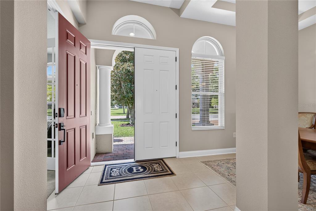A tiled entryway features an open red front door, a white door, and arched windows — 31948 GEOFF WAY, SORRENTO, FL