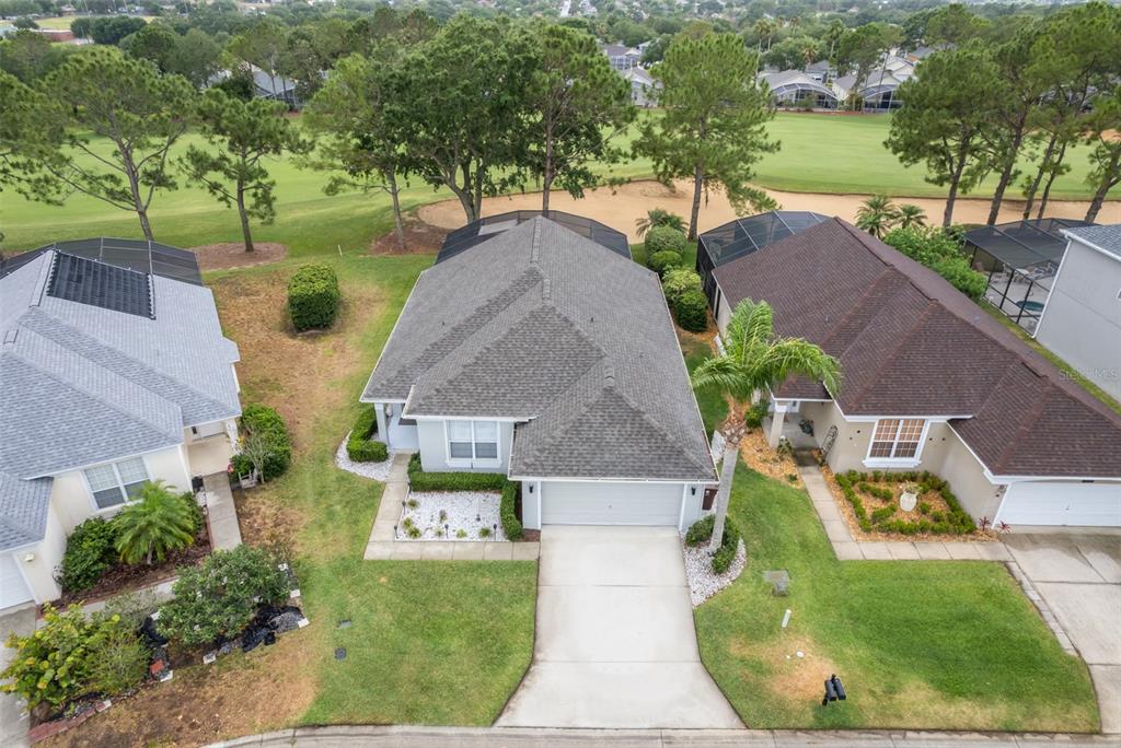 An aerial view shows three suburban houses with driveways and backyards bordering a golf course — 1430 PARK PLACE, HAINES CITY, FL