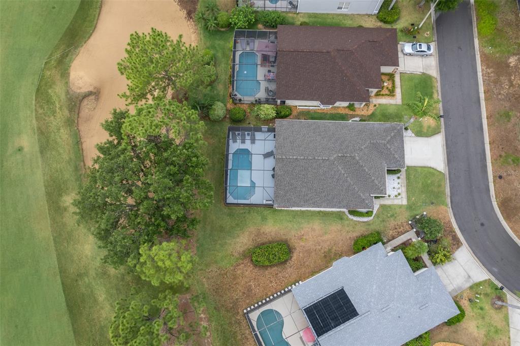 An aerial view shows three houses with screened-in pools situated next to a golf course — 1430 PARK PLACE, HAINES CITY, FL