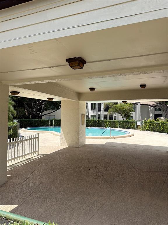 A covered patio overlooks a swimming pool surrounded by a fence and apartment buildings — 700 STARKEY ROAD UNIT 1311, LARGO, FL