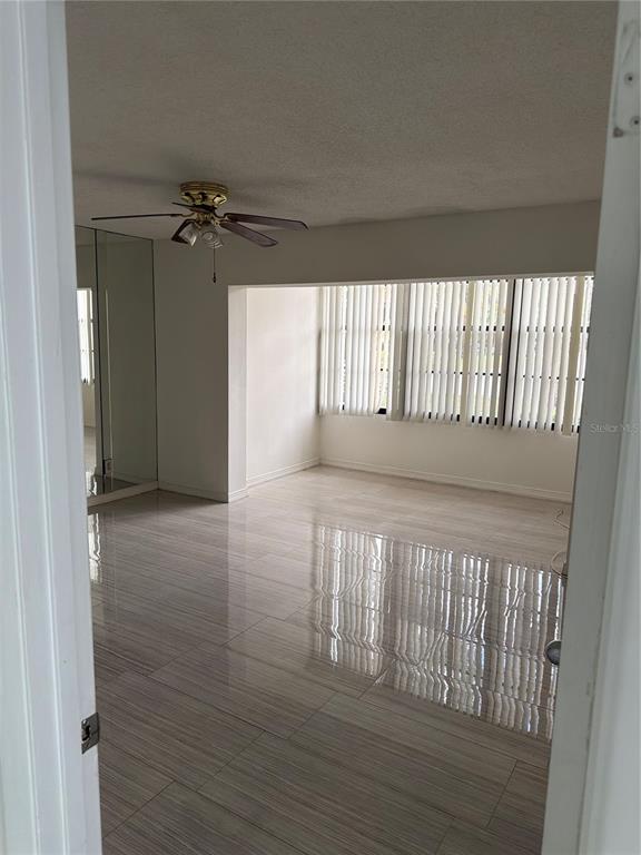 An empty room features light-colored tile flooring, a ceiling fan, and large vertical window blinds — 700 STARKEY ROAD UNIT 1311, LARGO, FL