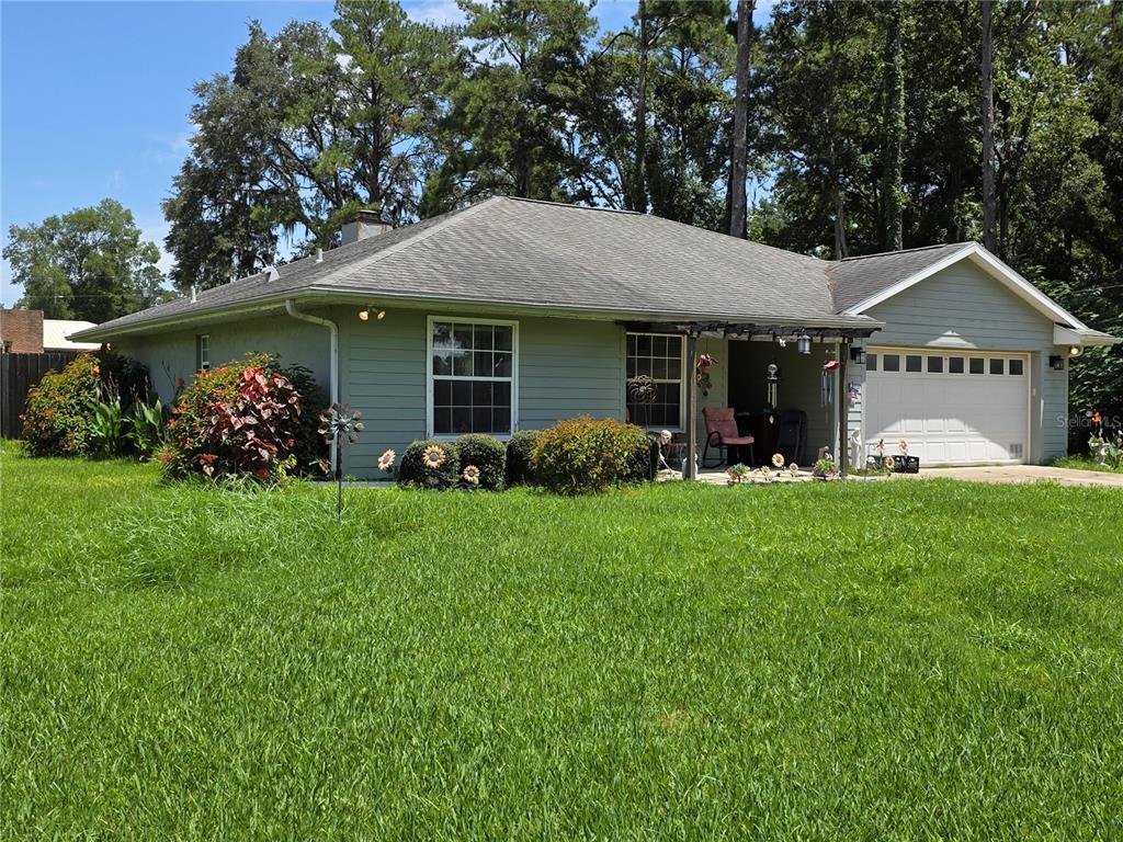 A single-story house with light green siding, a two-car garage, and a front porch — 5911 SE 127TH PLACE, BELLEVIEW, FL