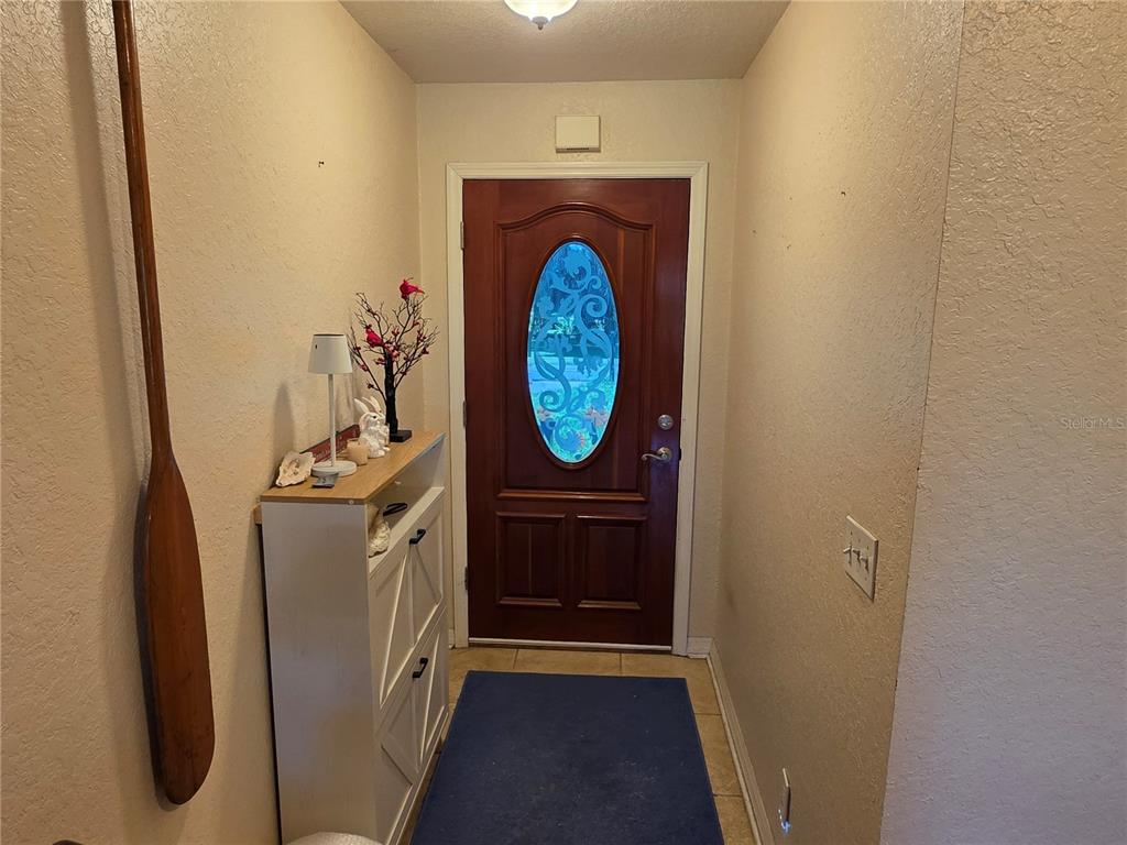 An entryway features a wooden front door with an oval glass insert and a shoe cabinet — 5911 SE 127TH PLACE, BELLEVIEW, FL