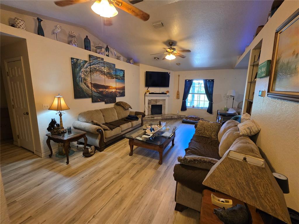 A living room features a fireplace, two sofas, a coffee table, and light wood flooring — 5911 SE 127TH PLACE, BELLEVIEW, FL