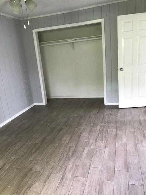 A room with gray wood-look flooring, paneled walls, a closet opening, and a white door — 4383 SE Field Street, Stuart FL 34997, STUART, FL