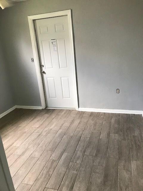 A room with gray walls, wood-look tile flooring, and a white six-panel door — 4383 SE Field Street, Stuart FL 34997, STUART, FL