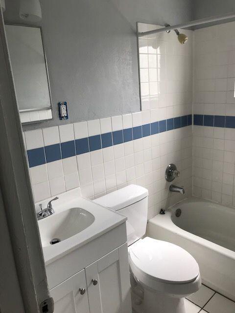A bathroom featuring a white vanity, a toilet, and a shower-tub combo with blue tiles — 4383 SE Field Street, Stuart FL 34997, STUART, FL