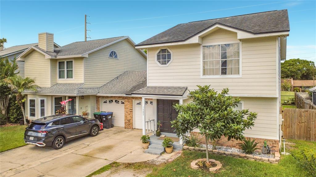 A two-story house with light siding, a dark roof, and a driveway with a parked car — 7987 SAGEBRUSH PLACE, ORLANDO, FL