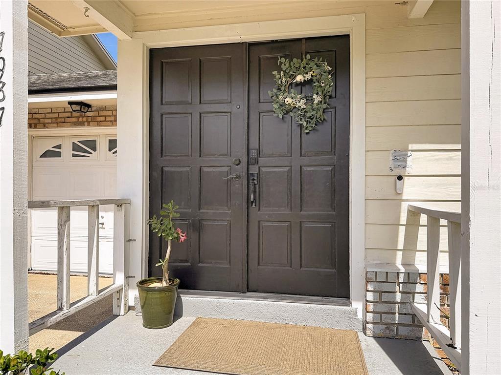 A dark brown double front door with a wreath sits on a covered porch — 7987 SAGEBRUSH PLACE, ORLANDO, FL