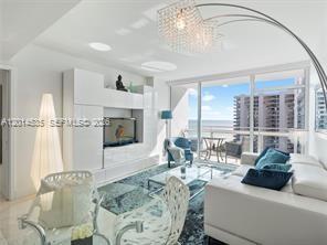 A modern living room features a white entertainment unit, a glass coffee table, and ocean views — 6801 Collins Ave, Miami Beach FL 33141, MIAMI BEACH, FL